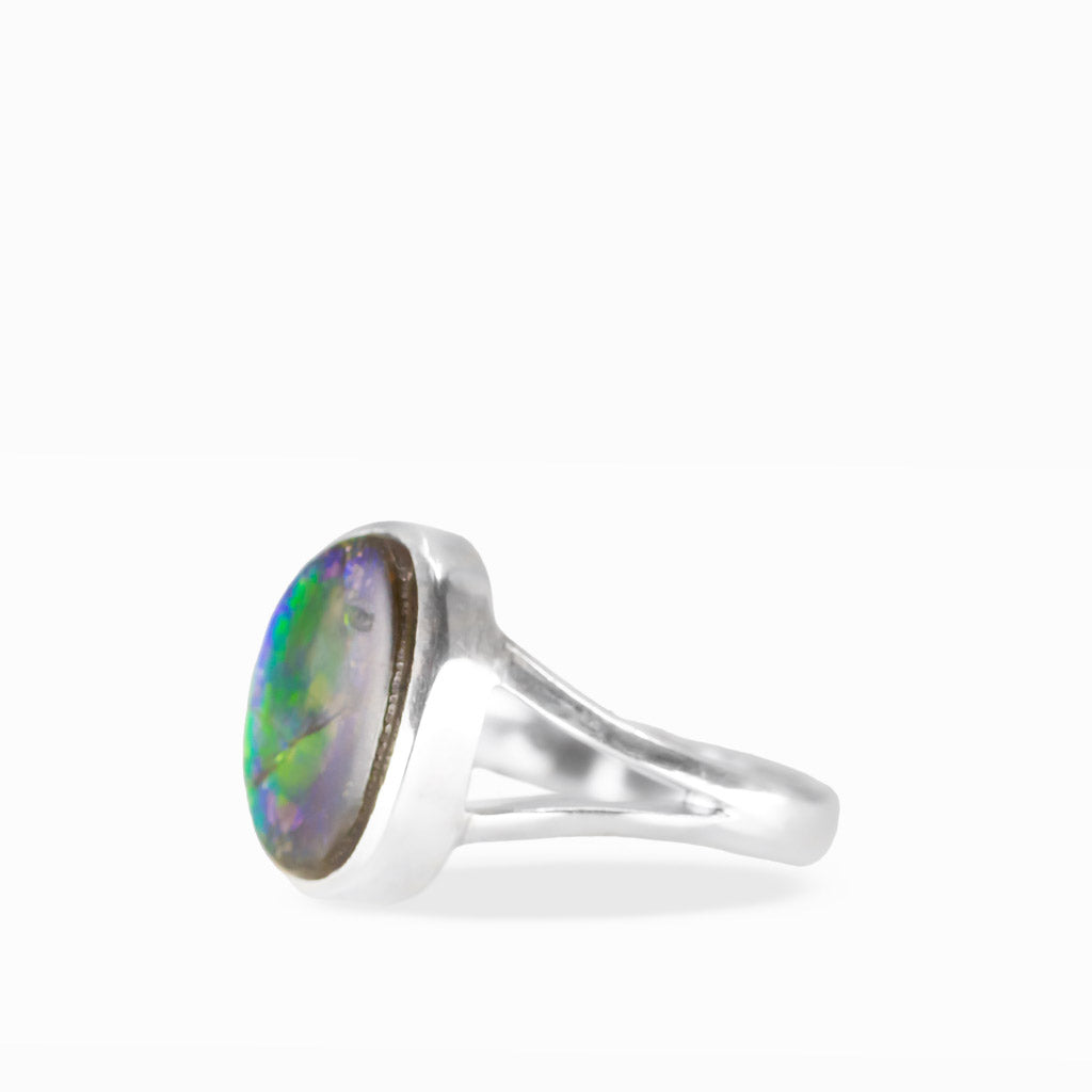Freeform Ammolite ring with brilliant green, golden-orange, and yellow iridescence, natural fracture patterns, and polished sterling silver split band.