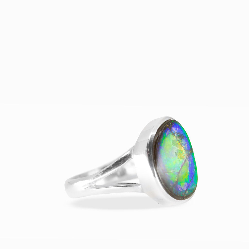 Freeform Ammolite ring with brilliant green, golden-orange, and yellow iridescence, natural fracture patterns, and polished sterling silver split band.