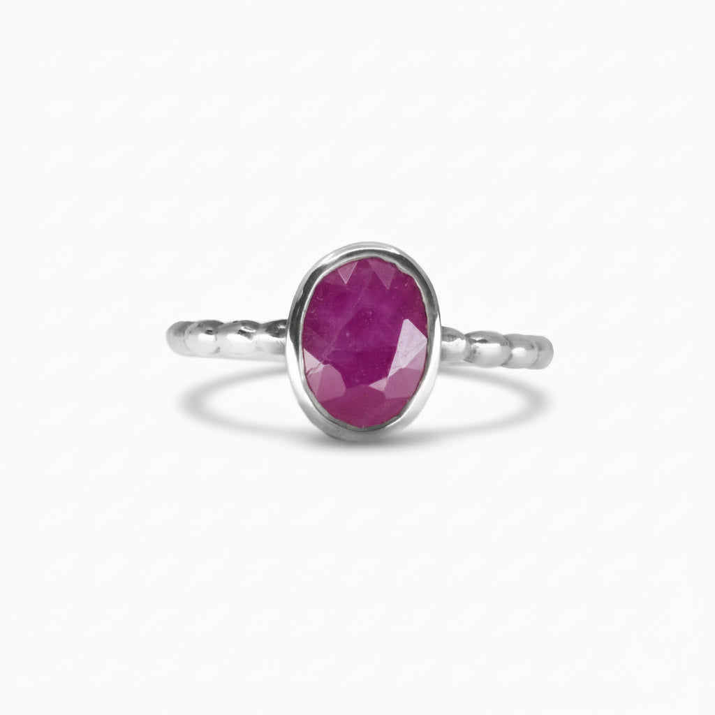 Faceted oval Ruby ring with vivid pink-crimson tones set in a polished sterling silver textured band on a white background. | MADE IN EARTH