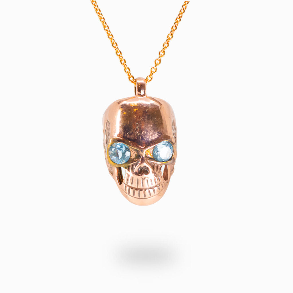 Rose gold skull pendant with blue topaz