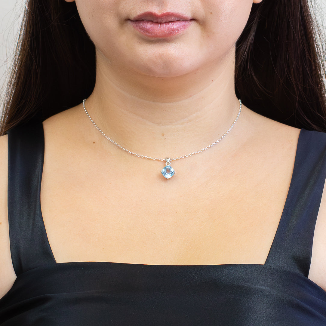Faceted blue topaz pendant in a sterling silver claw setting on a chain ON MODEL. | MADE IN EARTH