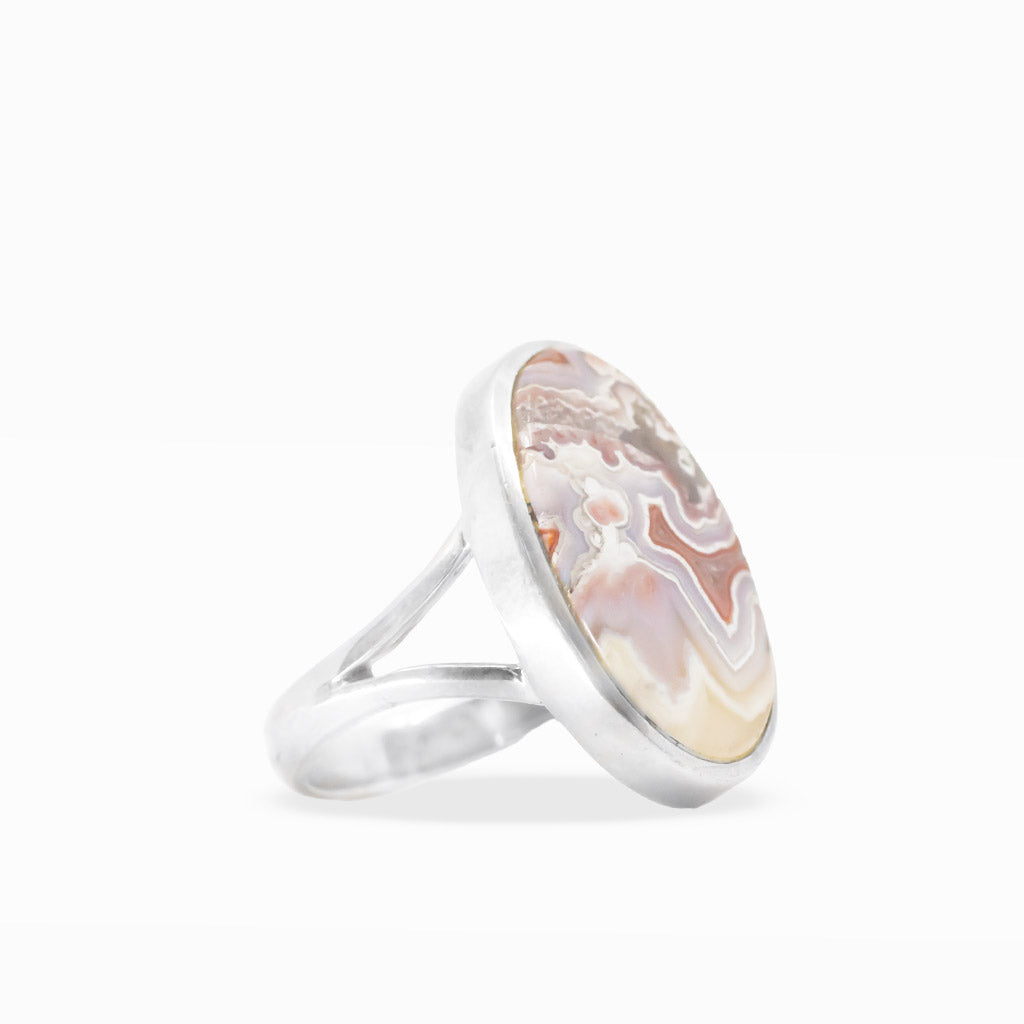 Oval Crazy Lace Agate ring with intricate cream, lavender, peach, and red banding in polished sterling silver bezel setting.