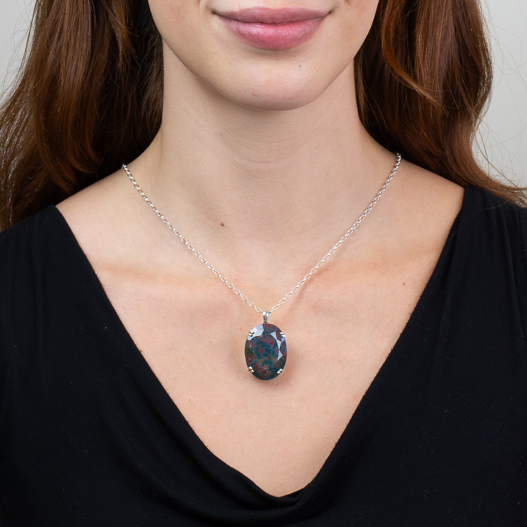 Faceted oval Bloodstone pendant necklace in sterling silver featuring natural deep green gemstone with red inclusions. ON MODEL