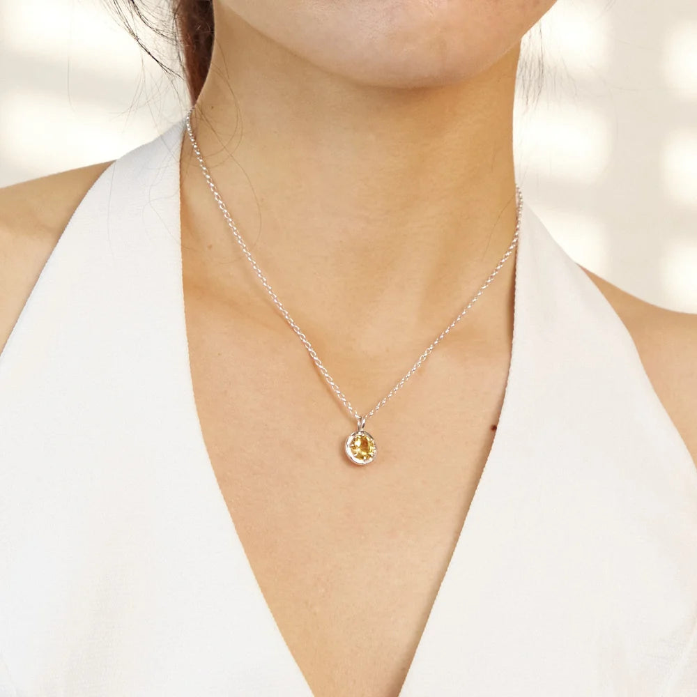 Round faceted golden-yellow Citrine gemstone set in polished sterling silver pendant necklace.