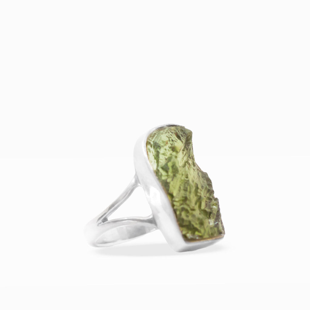 Translucent olive-green freeform Moldavite ring with textured natural surface, sterling silver bezel setting, and split band.