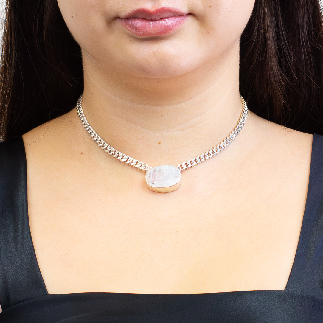 Raw oval Rainbow Moonstone bezel set in sterling silver on a silver chain with natural blue flash and iridescent tones on model. | MADE IN EARTH
