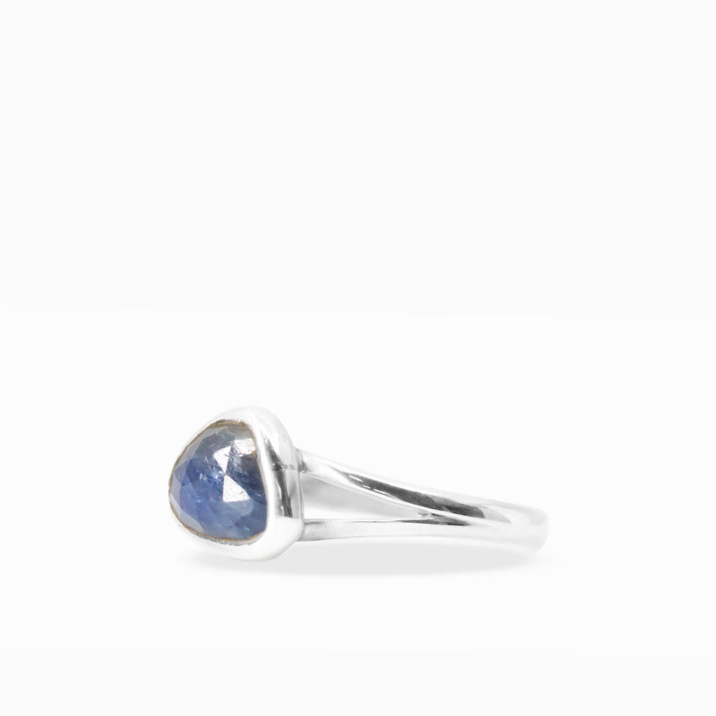 Deep midnight-blue freeform triangular Sapphire ring with faceted gemstone surface, sterling silver bezel setting, and split band.