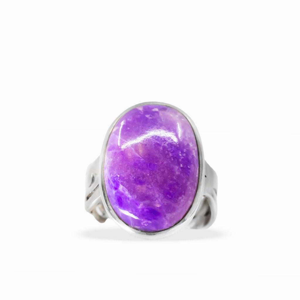 Large oval purple Sugilite ring with lavender marbling, polished sterling silver bezel setting, and decorative split band.