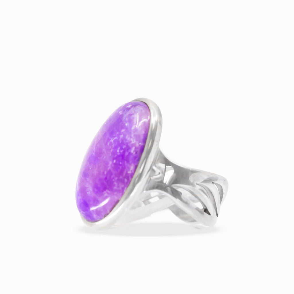 Large oval purple Sugilite ring with lavender marbling, polished sterling silver bezel setting, and decorative split band.