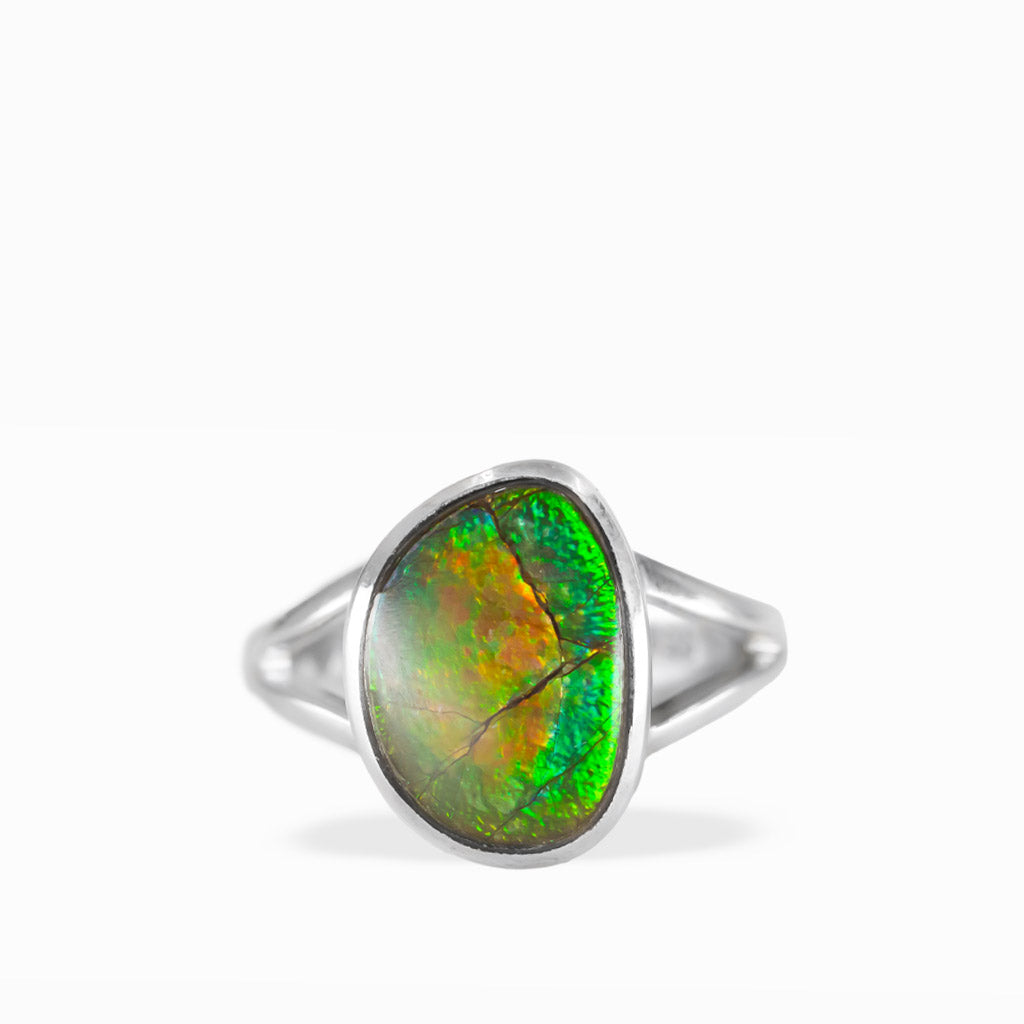 Freeform Ammolite ring with brilliant green, golden-orange, and yellow iridescence, natural fracture patterns, and polished sterling silver split band.