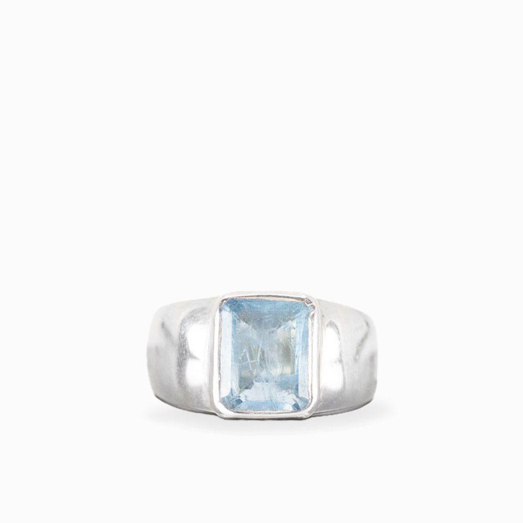 Emerald-cut Aquamarine ring with faceted pale ice-blue gemstone, polished sterling silver bezel setting, and wide smooth band.