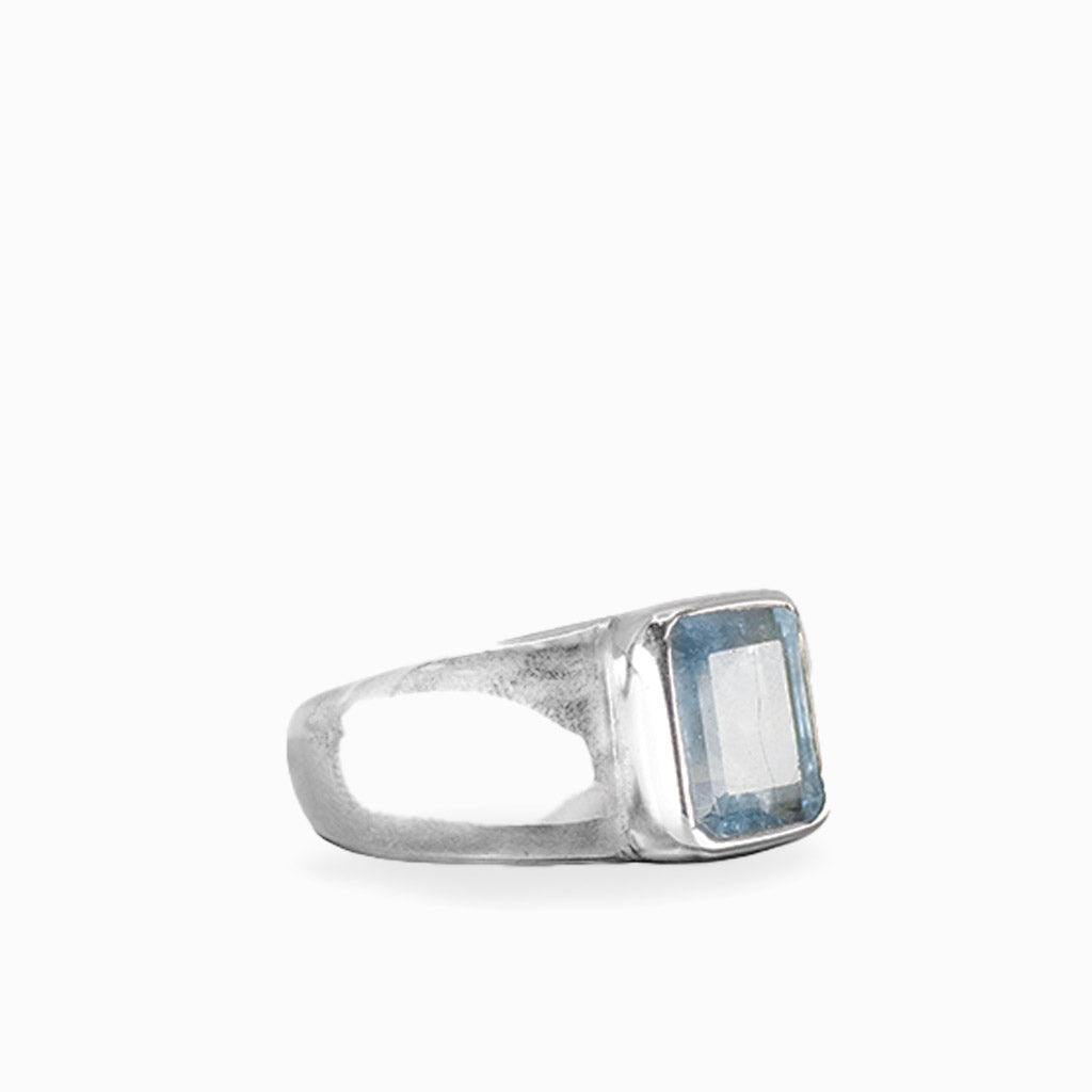 Emerald-cut Aquamarine ring with faceted pale ice-blue gemstone, polished sterling silver bezel setting, and wide smooth band.