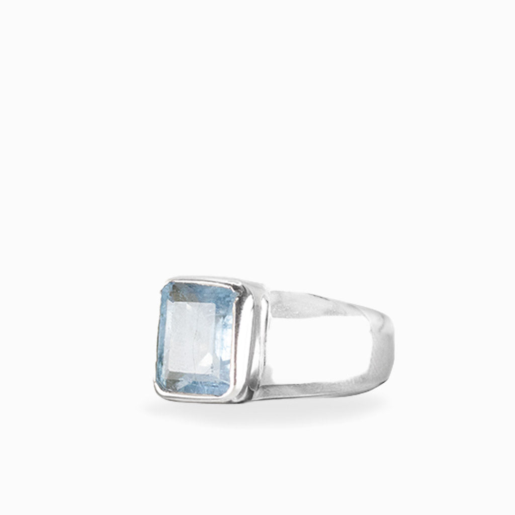 Emerald-cut Aquamarine ring with faceted pale ice-blue gemstone, polished sterling silver bezel setting, and wide smooth band.