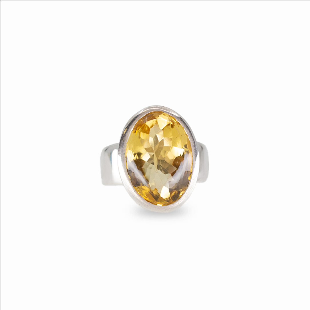 Faceted oval citrine gemstone ring set in sterling silver on white background