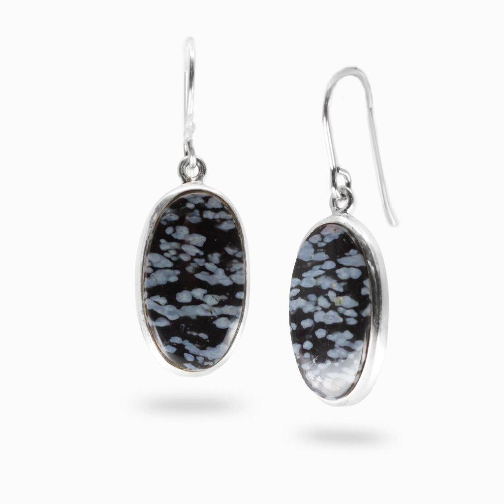 A pair of silver drop earrings featuring oval-shaped snowflake obsidian , shown against a plain white background.