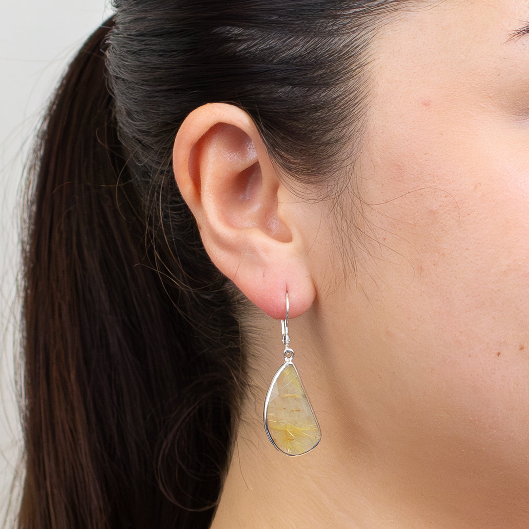 Faceted golden rutilated quartz drop earrings with visible gold rutile threads set in sterling silver lever-back hooks. | MADE IN EARTH