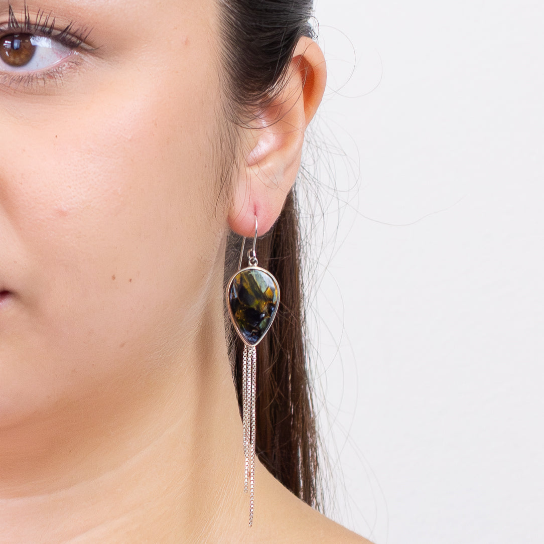 Pietersite teardrop earrings in sterling silver with chain-fringe drops and swirling blue-gold patterns on model| MADE IN EARTH