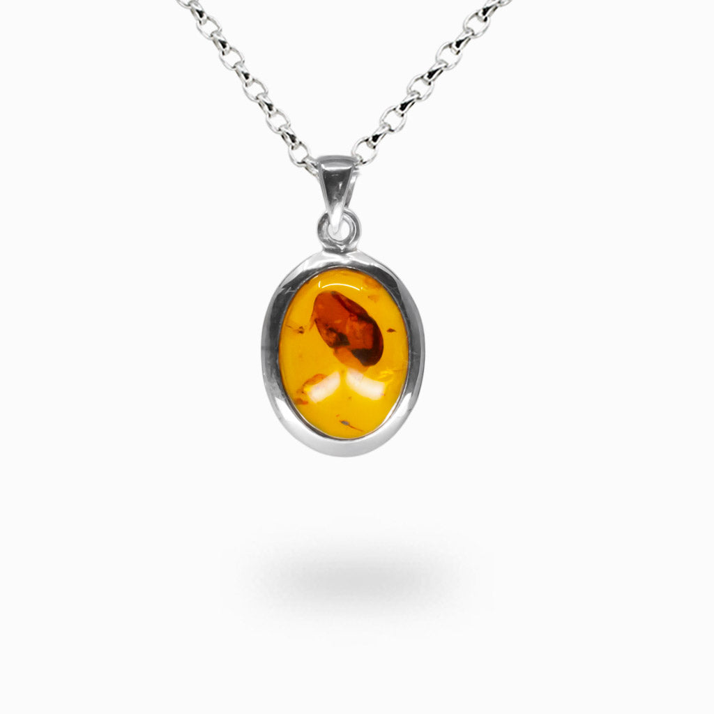 Oval cabochon amber pendant set in sterling silver bezel featuring warm golden fossilized resin tones
