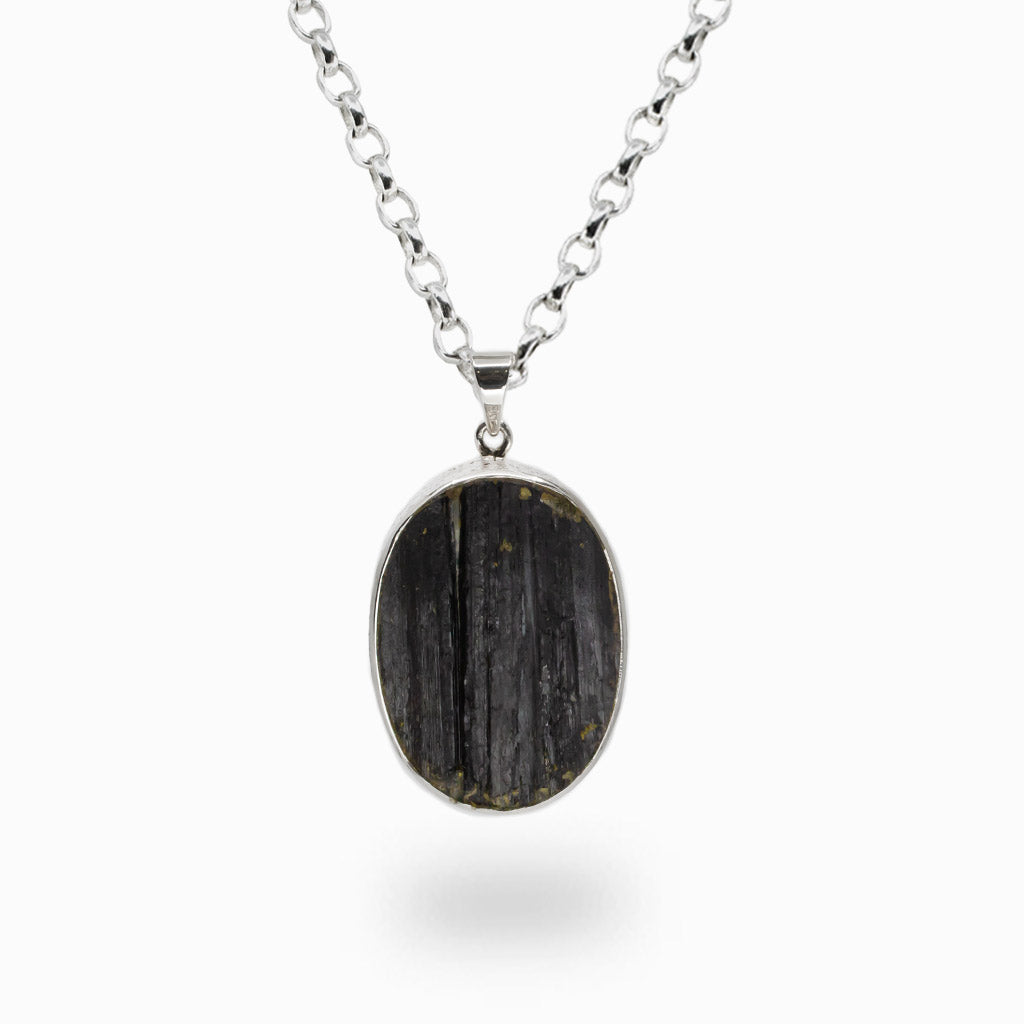 Raw oval Black Tourmaline pendant necklace in sterling silver bezel setting featuring natural crystal texture and striations.