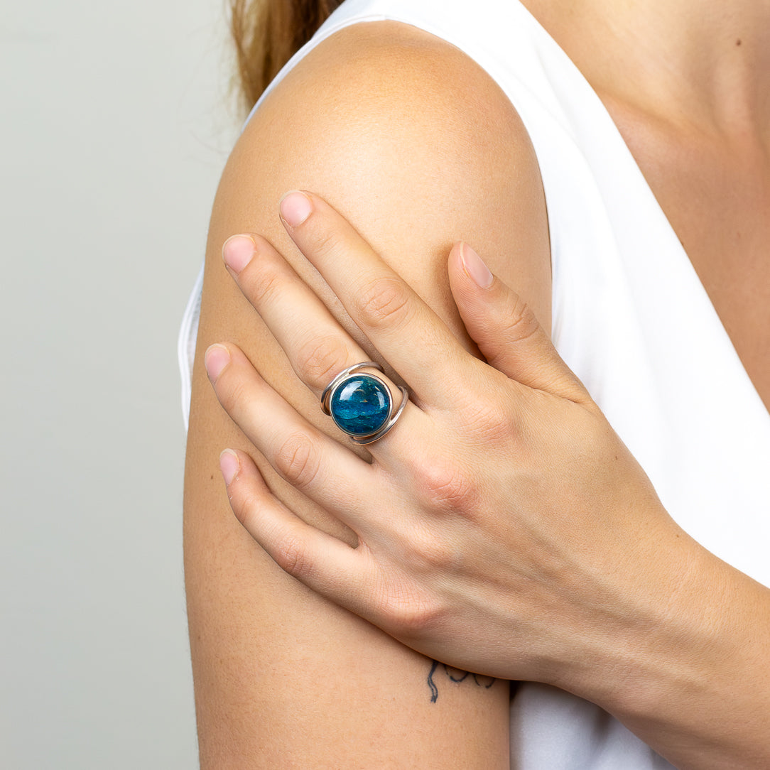 Round Blue Apatite ring with vivid turquoise-blue cabochon, natural inclusions, polished sterling silver bezel, and openwork band.