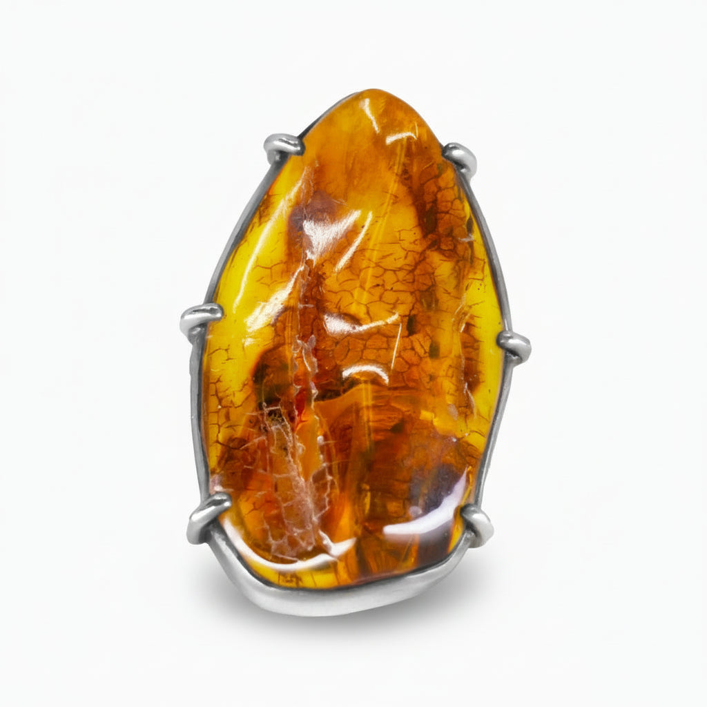 Organic-shaped Amber ring with warm golden-orange tones and natural inclusions set in a sterling silver prong setting on a white background. | MADE IN EARTH USA