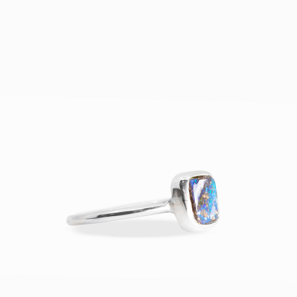Rectangular Boulder Opal ring with electric blue and green flashes, natural brown ironstone matrix, and sterling silver bezel setting.