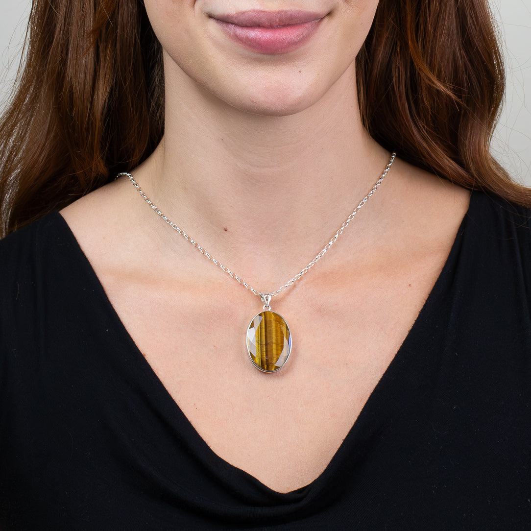 Faceted oval Tiger Eye pendant necklace in sterling silver featuring golden brown bands with natural chatoyancy. ON MODEL