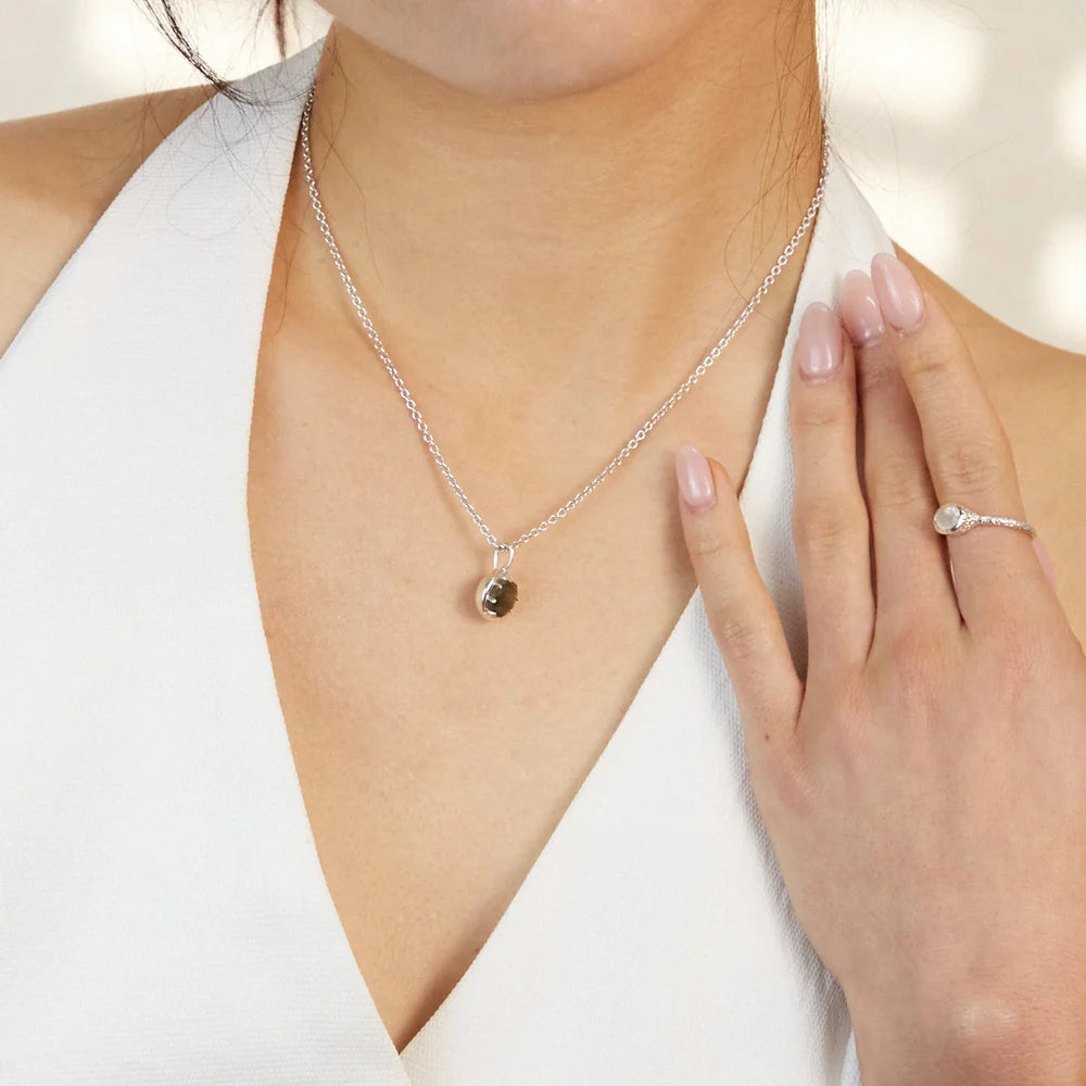 Round faceted Labradorite gemstone with blue-violet flash set in polished sterling silver pendant necklace.