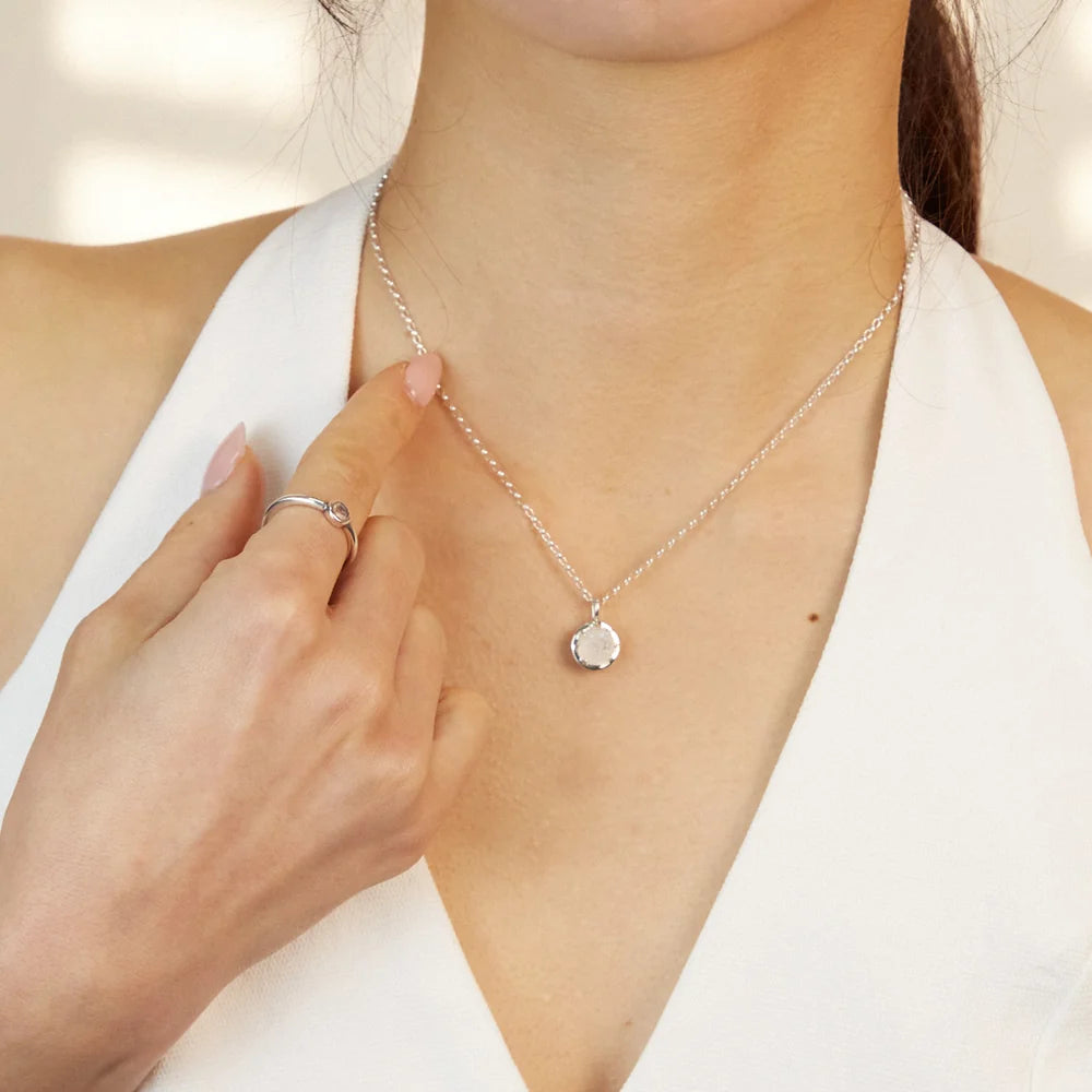 Round faceted Rainbow Moonstone with soft blue flash set in polished sterling silver pendant necklace.