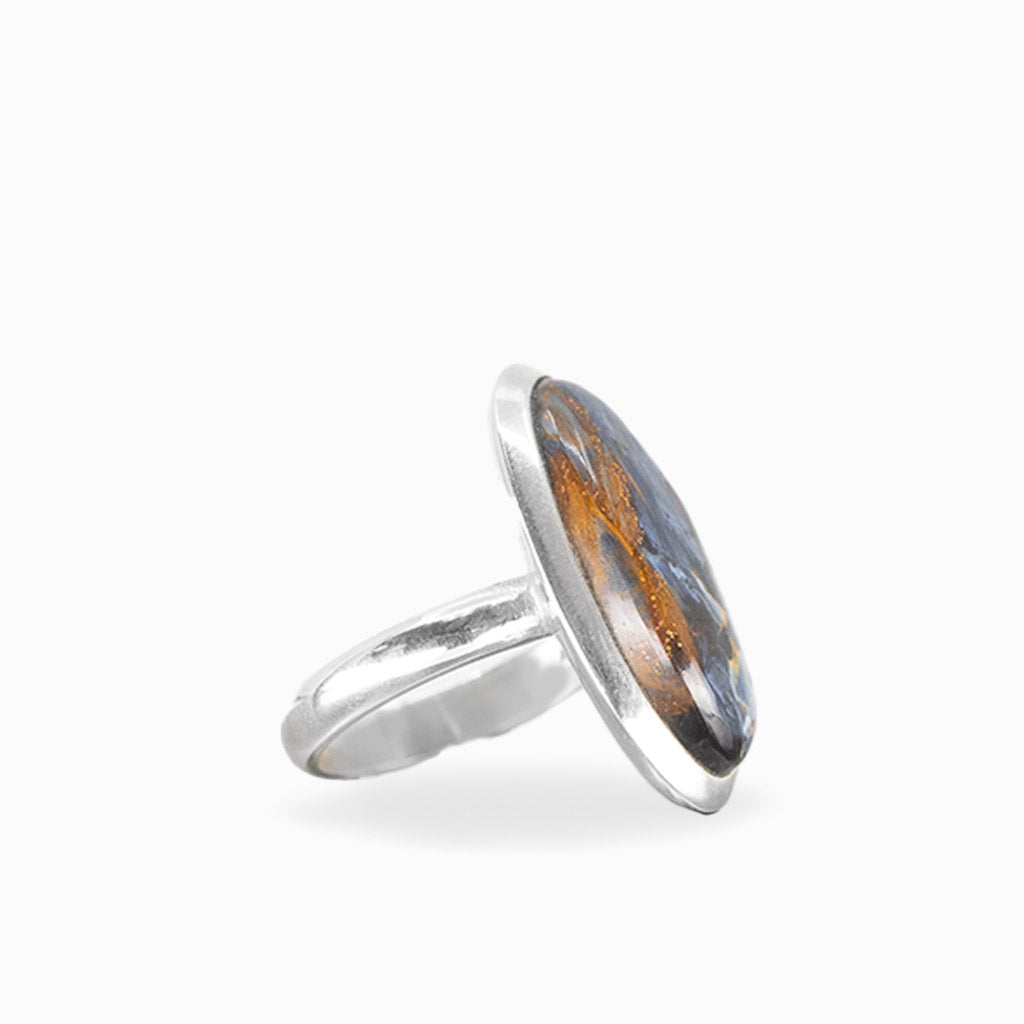 Elongated oval Pietersite ring with swirling midnight-blue, charcoal, and golden-brown patterns in polished sterling silver.
