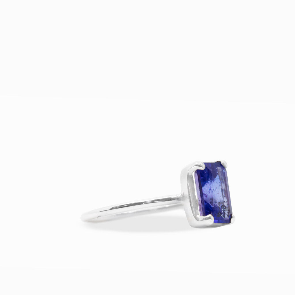 Vibrant violet-blue emerald-cut Tanzanite ring with four-prong sterling silver setting and polished slim band.