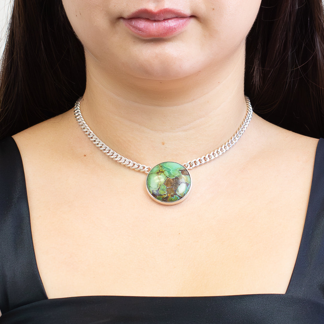Round Tibetan turquoise cabochon pendant with blue and green tones and dark matrix set in sterling silver chain necklace on model . | MADE IN EARTH