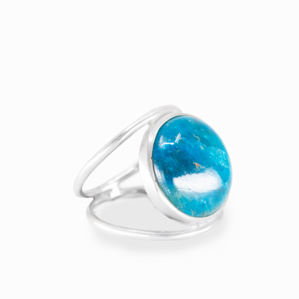Round Blue Apatite ring with vivid turquoise-blue cabochon, natural inclusions, polished sterling silver bezel, and openwork band.