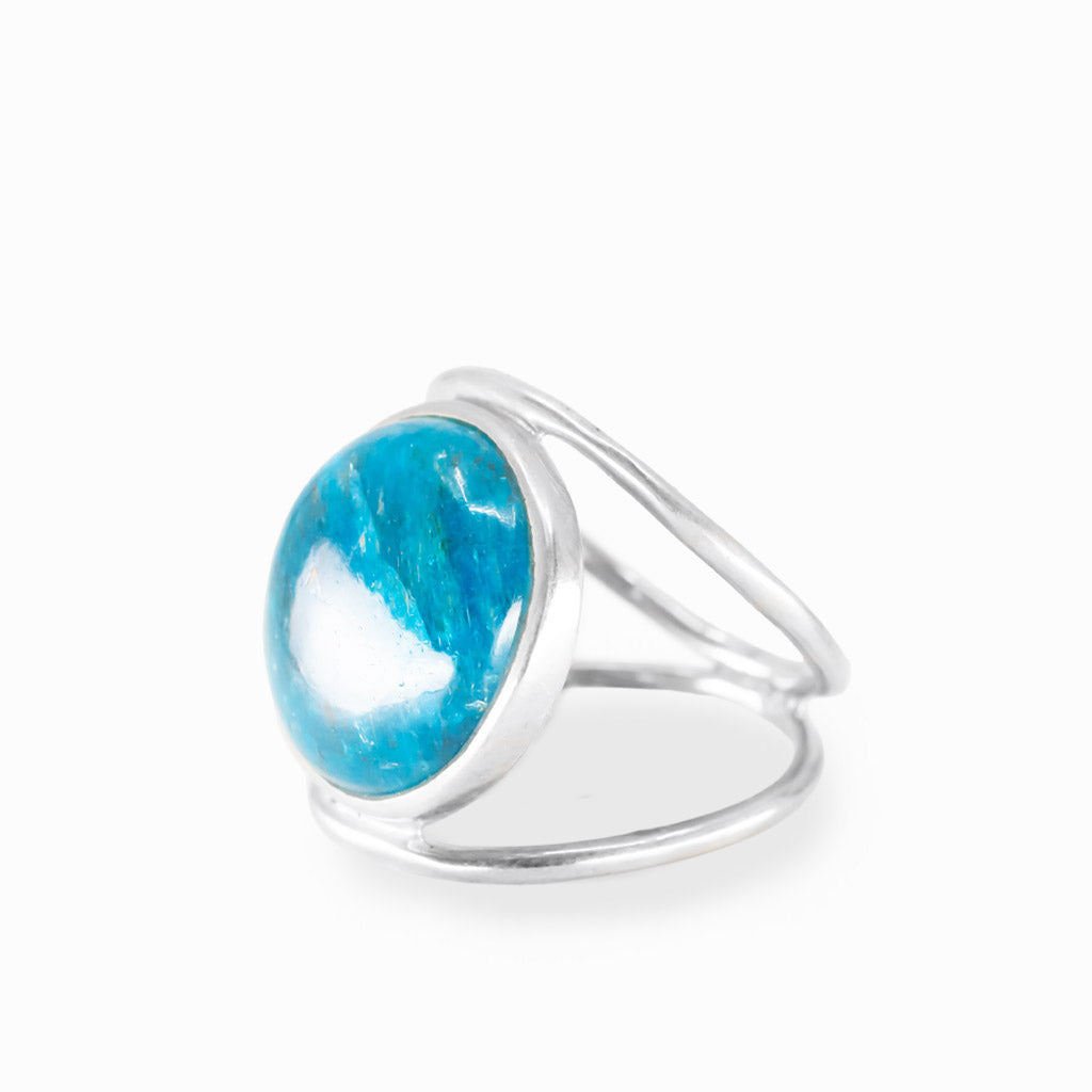 Round Blue Apatite ring with vivid turquoise-blue cabochon, natural inclusions, polished sterling silver bezel, and openwork band.