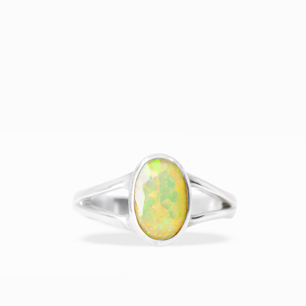 Oval Precious Opal ring with luminous green, yellow, and orange play-of-color, sterling silver bezel setting, and open split band.